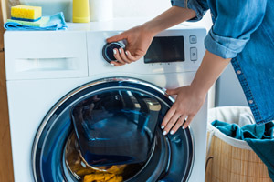 Person using new washing machine in home. D&F Plumbing, Heating and Cooling provides professional washing machine installation services in Portland OR & Vancouver WA.
