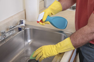 Man cleaning the kitchen sink. D & F Plumbing serving Portland OR and Vancouver WA talks about spring plumbing tips.