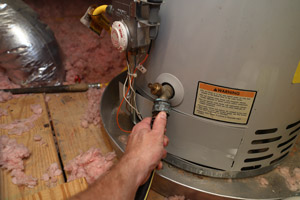 Person fixing water heater. D&F Plumbing, Heating and Cooling, serving Portland OR & Vancouver WA provides water heater maintenance services.