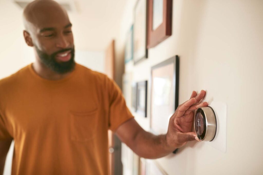 Man adjusting thermostat indoors