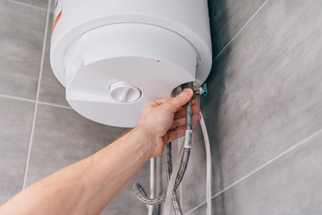 cropped shot of male plumber repairing electric boiler in bathroom