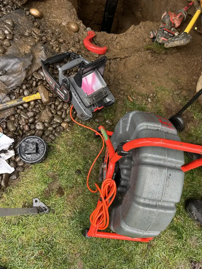 D&F sewer camera reel and monitor on the lawn beside an open dig